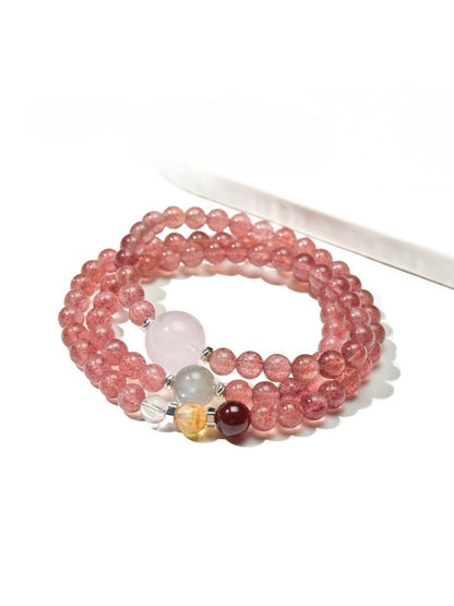 Lovra triple wrap bracelet with pink crystal beads and gold accents on a white background