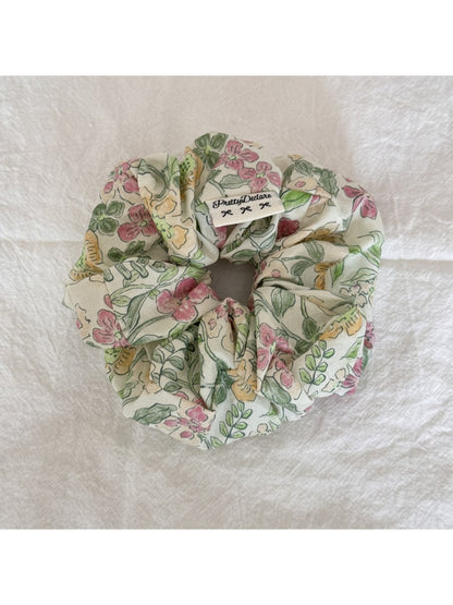 Gifty Sweet Green Style Scrunchie styled in a ponytail on a model with brown hair