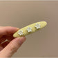 Yellow tiny floral hair clip placed next to matching fabric swatches