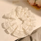 Close-up of minimalist white ruffled scrunchie on a plain background