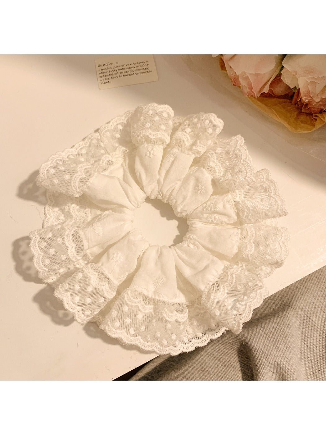 Close-up of minimalist white ruffled scrunchie on a plain background