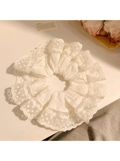 Close-up of minimalist white ruffled scrunchie on a plain background