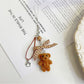 Keypus bear bag charm hanging from a backpack zipper pull