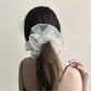 Gifty scrunchie styled on a wrist, highlighting its double layer ruched design