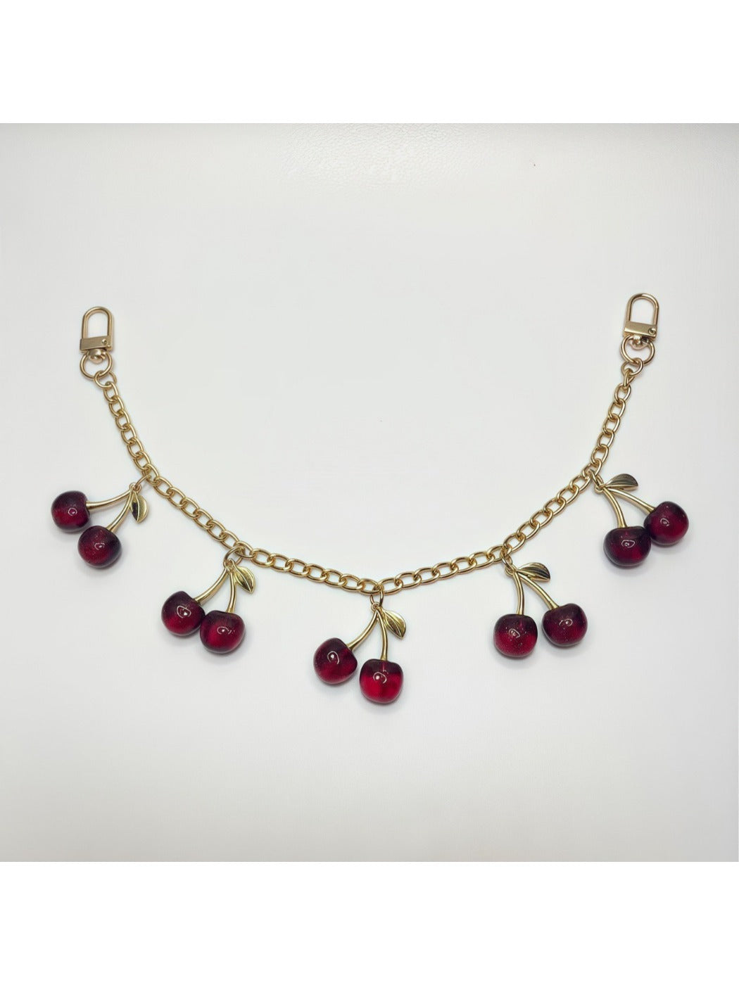 Cherry bag charm shown with a set of colorful keys on a wooden table