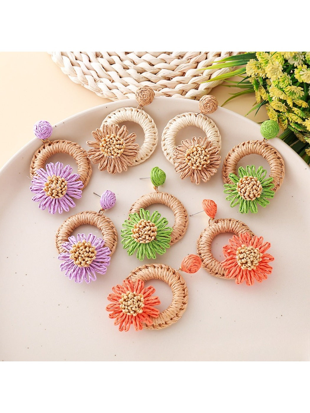 Close-up of Earedge raffia daisy shaped stud earrings on white background