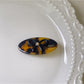 Oval butterfly hair clip clipped onto a strand of hair close-up