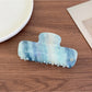 Beau gradient acetate claw clip resting on a wooden surface with natural light