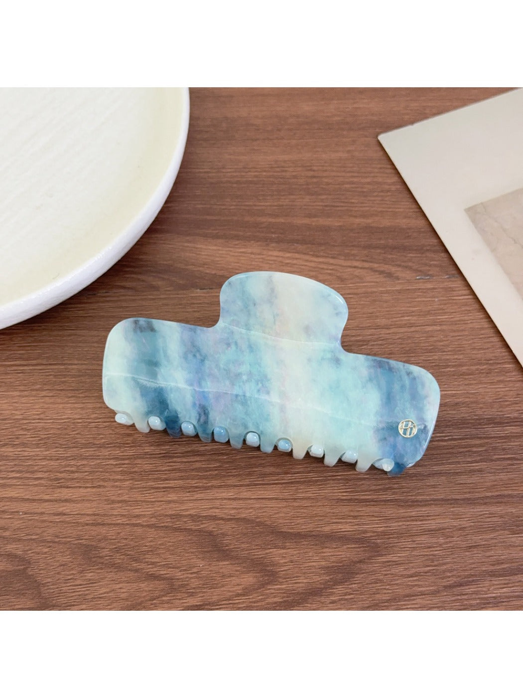 Beau gradient acetate claw clip resting on a wooden surface with natural light