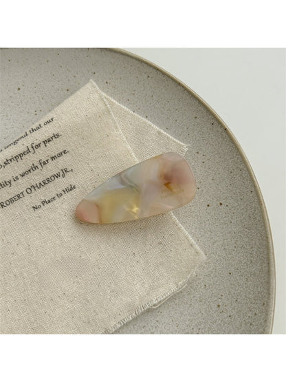 Beau hair clip resting on a wooden surface with natural light