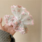 Pink ruffled scrunchie wrapped around a ponytail on a model