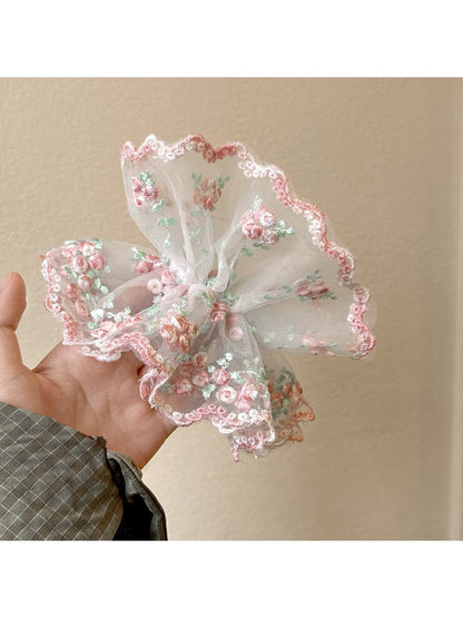 Pink ruffled scrunchie wrapped around a ponytail on a model