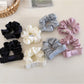 Close-up of a minimalist satin bow scrunchie in soft beige on a white background