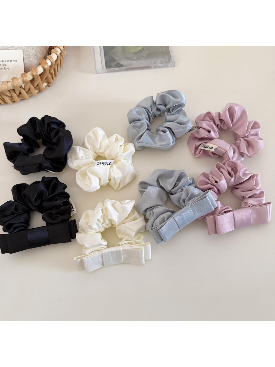 Close-up of a minimalist satin bow scrunchie in soft beige on a white background