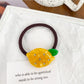 Close-up of a yellow hair tie with a lemon charm on a wooden background