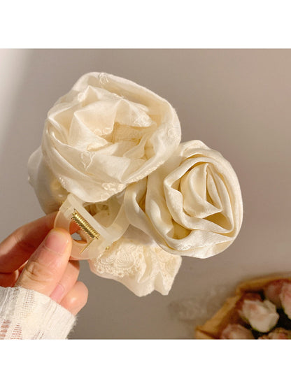 Beau rose decorated hair claw clip held in hand to show size and intricate details