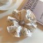Side view of Gifty satin scrunchie highlighting gathered elastic and floral pattern