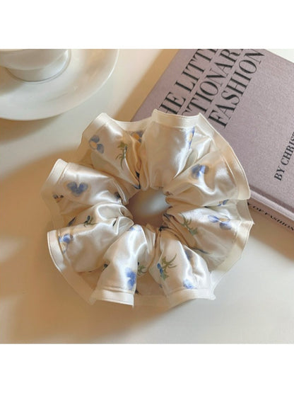 Side view of Gifty satin scrunchie highlighting gathered elastic and floral pattern