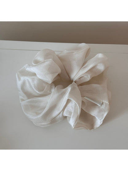 Scrunchie styled on a wrist as a fashion accessory with soft pastel tones