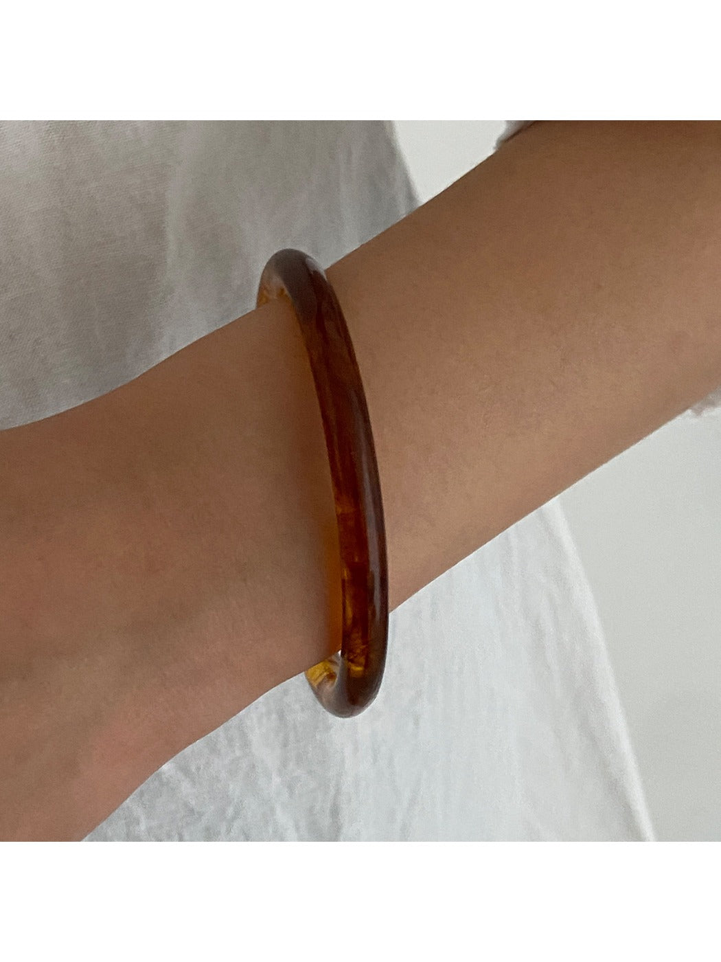 Lovra wide round bangle bracelet photographed with soft shadows emphasizing its round shape