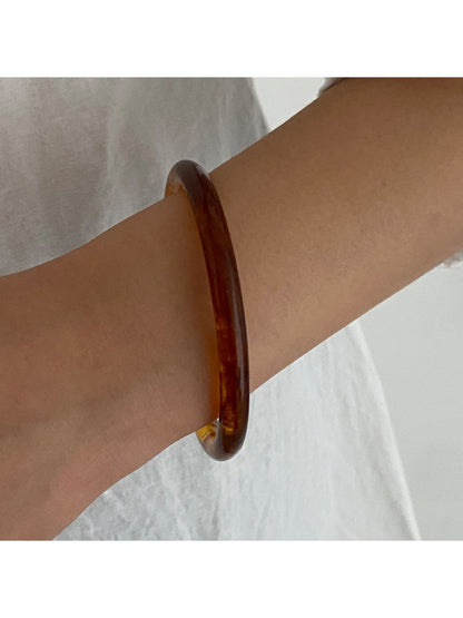 Lovra wide round bangle bracelet photographed with soft shadows emphasizing its round shape