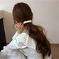 Gifty bow embellished hair tie wrapped around a ponytail on a model