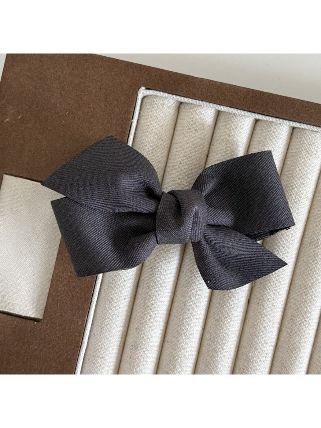 Beau satin bow hair clip held in hand showing size and shape