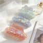 Beau mermaid claw clip showing curved prongs and holographic colors