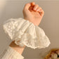 White fabric scrunchie with delicate ruffles displayed flat
