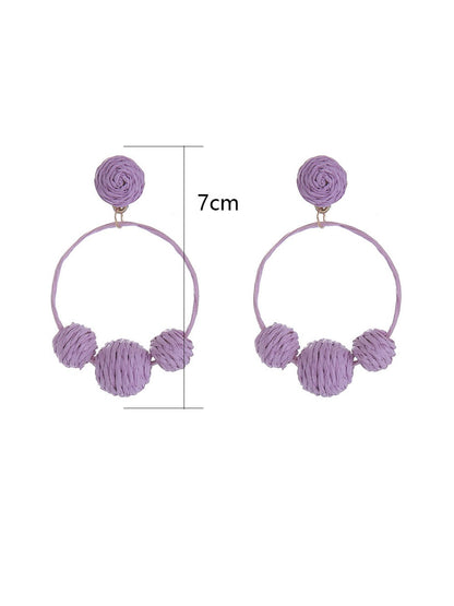 Earedge raffia round ball earrings hanging on a white display stand