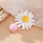 Beau raffia strawberry flower hair clip shown from above on a neutral background