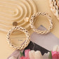 Pair of Earedge rattan round hollow earrings hanging on a jewelry stand