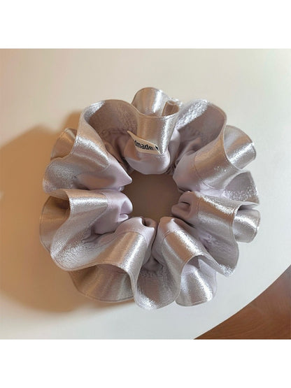 Silver satin scrunchie displayed flat highlighting ruffle details