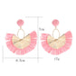 Earedge raffia fan earrings hanging on a wooden display stand