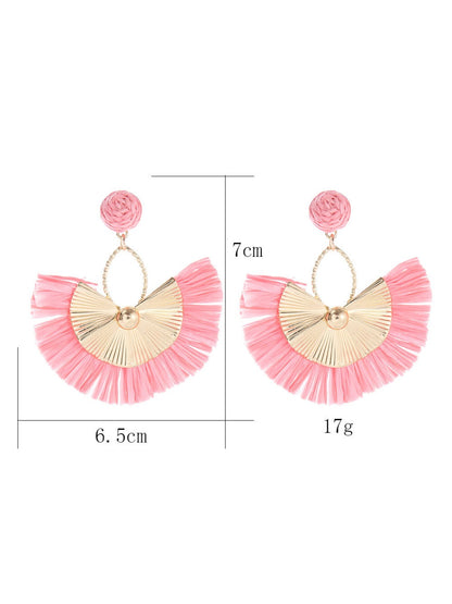 Earedge raffia fan earrings hanging on a wooden display stand