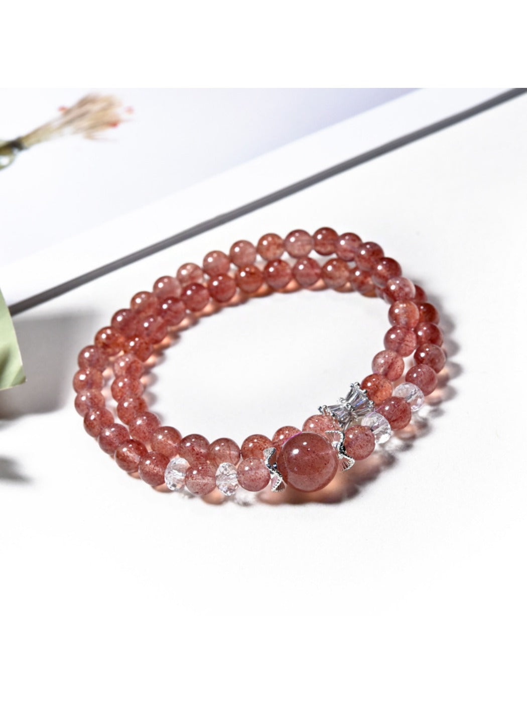 Close-up of strawberry quartz beads on Lovra multi-wrap bracelet with silver detailing