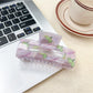 Beau claw clip resting on a fabric surface highlighting the vibrant fruit pattern