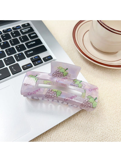 Beau claw clip resting on a fabric surface highlighting the vibrant fruit pattern