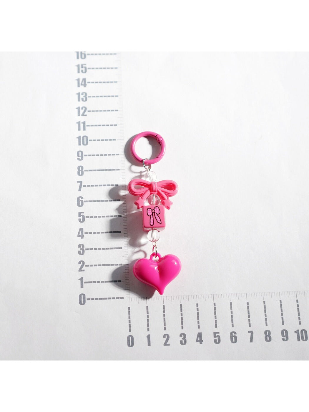 Hand holding Keypus bow heart beaded keychain showing its size and details