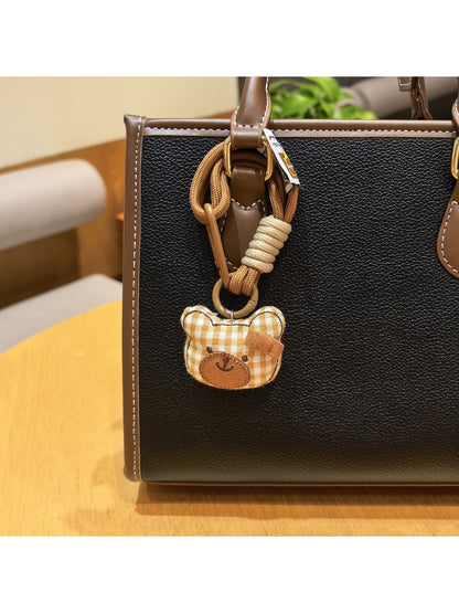 Bear charm keychain held in a hand to show size and texture