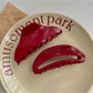 Close-up of Beau red acetate hair clip with glossy finish on white background