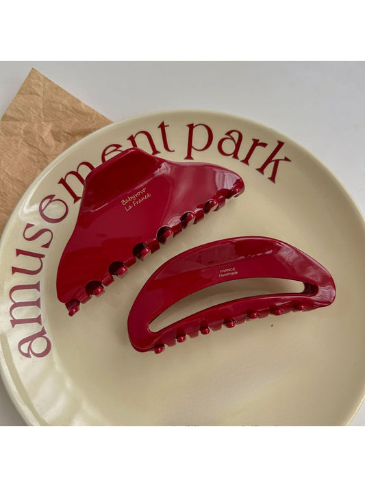 Close-up of Beau red acetate hair clip with glossy finish on white background