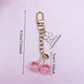Hand holding the cherry charm keychain showing its size and design details
