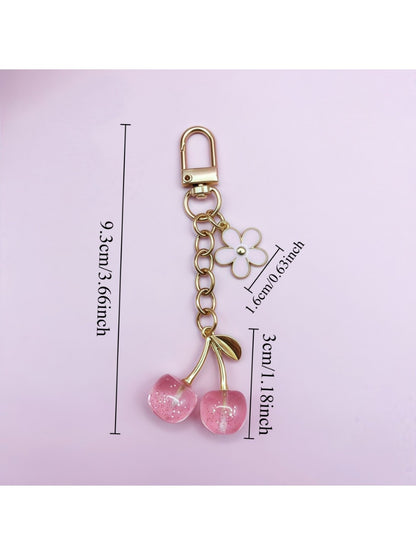 Hand holding the cherry charm keychain showing its size and design details