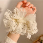 White tulle scrunchie with black polka dots styled in a ponytail