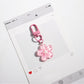 Flower keychain displayed on a light fabric background with soft lighting