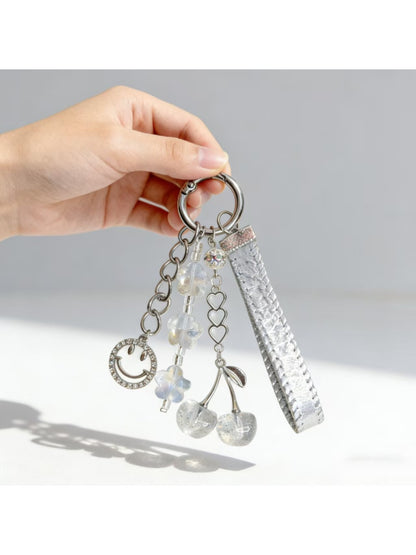 Minimalist cherry charm keychain attached to a set of keys on wooden surface