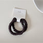 Gifty satin hair tie displayed alongside matching minimalist accessories