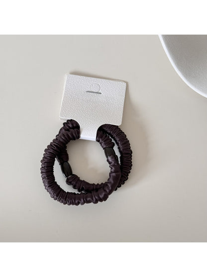 Gifty satin hair tie displayed alongside matching minimalist accessories