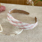 Gifty headband wrapped around wrist, highlighting minimalist plaid and stripe pattern